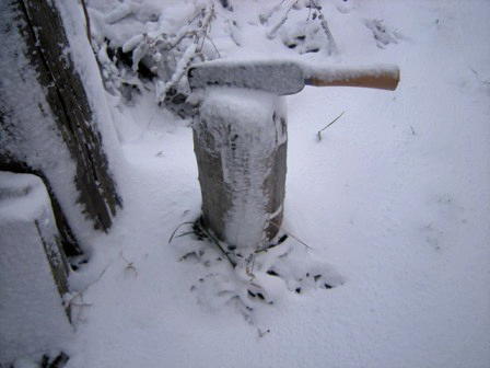 Schittstock mit Beil in die weisse Pracht Schnee gehüllt.